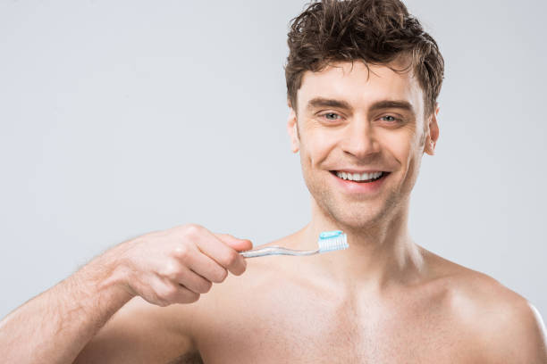 istock smiling man holding toothbrush with toothpaste, isolated on grey 1097381218