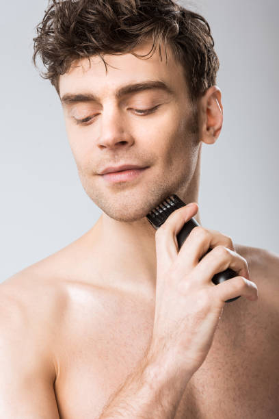 istock young man shaving with electric razor isolated on grey 1097381248