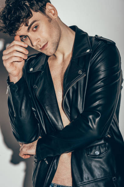 istock handsome sexy man posing in black leather jacket on grey 1097382752