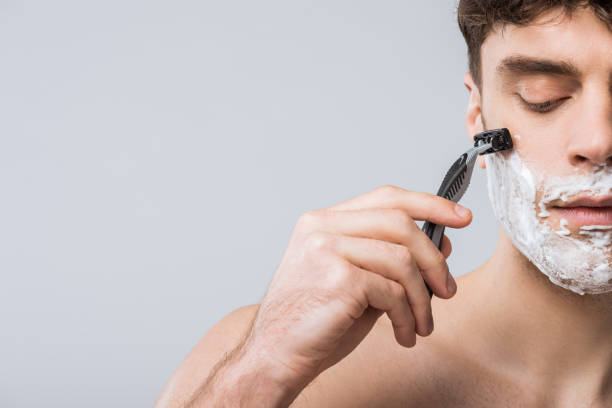 handsome young man foam on face shaving with razor, isolated on grey handsome young man foam on face shaving with razor, isolated on grey shaving stock pictures, royalty-free photos & images