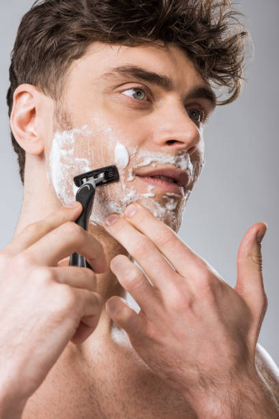 istock handsome man foam on face shaving with razor, isolated on grey 1097383904