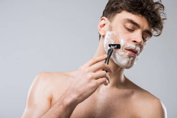 istock handsome caucasian man foam on face shaving with razor, isolated on grey 1097383914