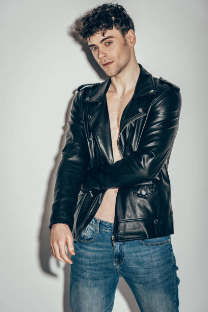 istock stylish sexy man posing in jeans and black leather jacket on grey 1097384012