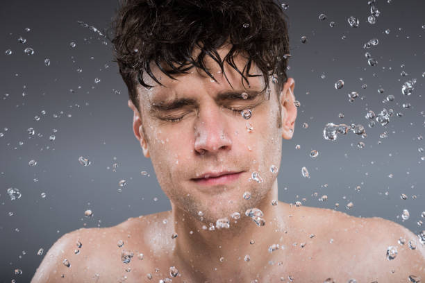 istock handsome man washing face with water, isolated on grey 1097385040