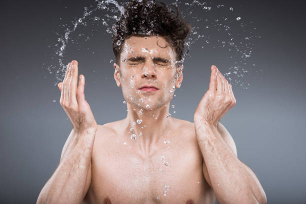 istock handsome man splashing water into face, isolated on grey 1097385044