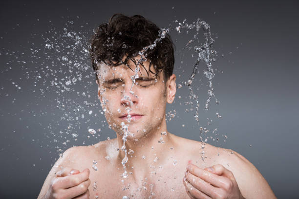 istock handsome man splashing water into face in the morning, isolated on grey 1097385054