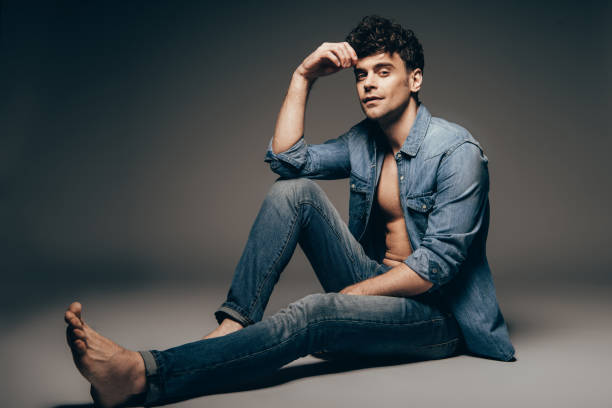 handsome young sexy man posing in jeans clothes on dark grey
