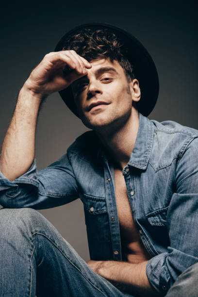 istock handsome man posing in denim clothes and hat isolated on dark grey 1097385174