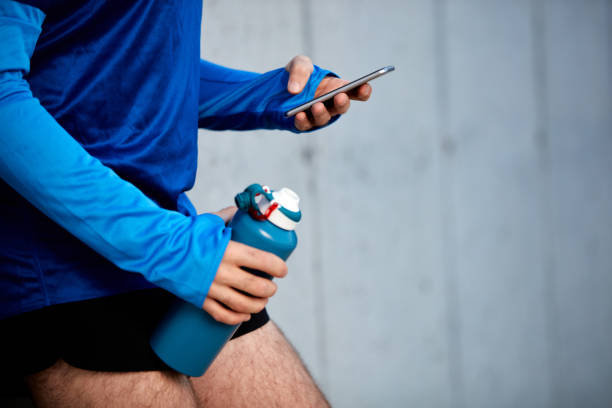 istock Close up of male runner leaning on wall and using smart phone. 1097385374