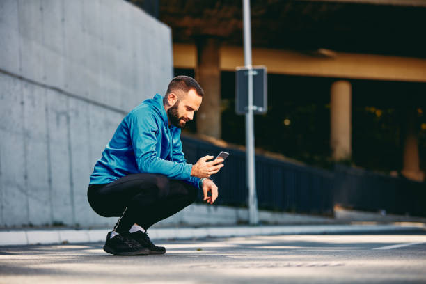 istock Sporty man crouching and using smart phone. 1097392094