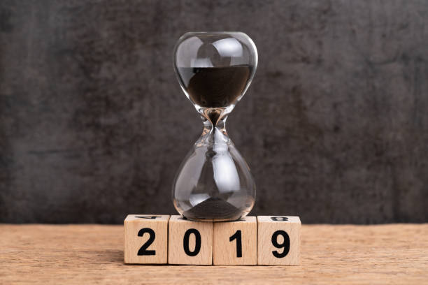 istock Year 2019 time countdown or time passing concept, hourglass or sandglass on cube wooden block building number 2019 on wood table with dark blackboard background with copy space 1097394844
