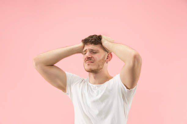 istock Man having headache. Isolated over pink background. 1097395036