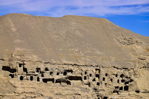 Landscape. Exterior view, many cave ruins inside a big sand dune, blue sky as background. Created in Dunhuang Mogao Cave, China, 07/07/2018