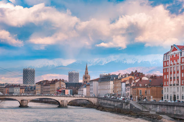 Church, Isere river and bridge in Grenoble, France Scenic view of the banks of the Isere river and bridge, Collegiate Church of Saint-Andre with French Alps on the background, Grenoble, France isere river stock pictures, royalty-free photos & images