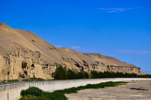 Landscape. The cave ruins by the side of a dried river, beautiful blue sky as background. Created in Dunhuang Mogao Caves, China, 07/07/2018
