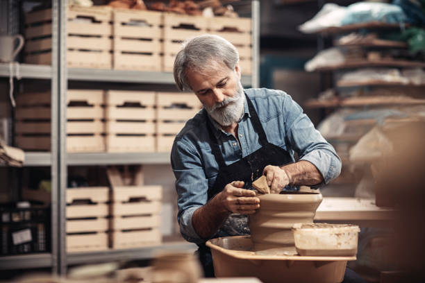 bärtigen alten handwerker in keramikwerkstatt - keramiker stock-fotos und bilder