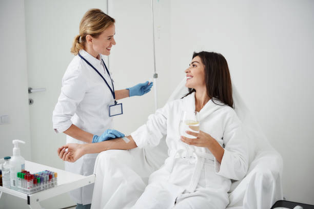 istock Doctor regulating intravenous drip while looking at young lady with smile 1097405576