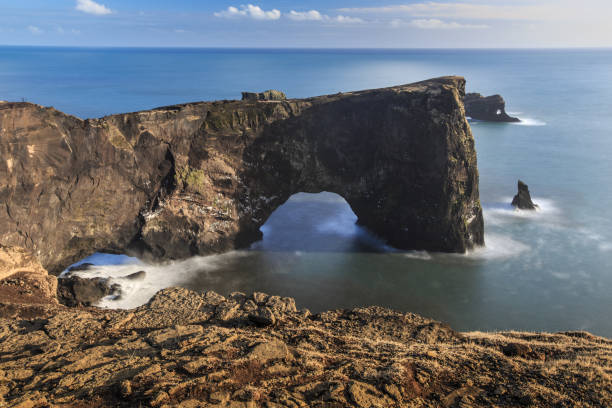 istock Long exposure of Dyrholaey Arch with smooth water 1097408564