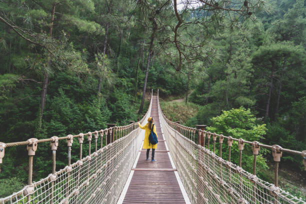 istock Woman with raincoat standing on suspension bridge. 1097409438