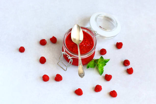 istock fresh raspberry jam in a glass jar, next to fresh raspberries and mint leaves. concept of homemade jam, preparation for winter, selective focus and copy space 1097412936