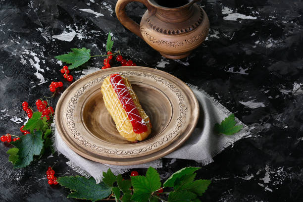 sweet cake with cream, jam with red berries currants on a brown clay plate, on dark background. Summer fruit dessert. Top view. Free copy space