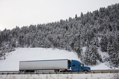 Semi-Trailer Truck Traveling across the Mountain in the Snow