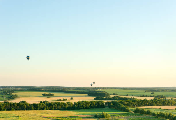Flying in a balloon over the fields. Cloudless summer day. Free space