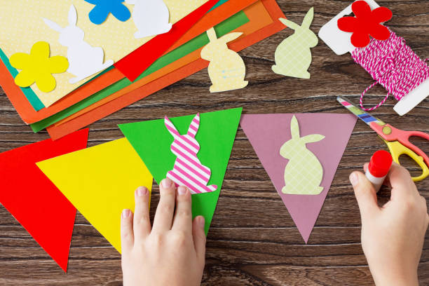 the child sticks details festive easter garland on a wooden background. project of children's creativity, handicrafts, crafts for kids. - 16707 imagens e fotografias de stock