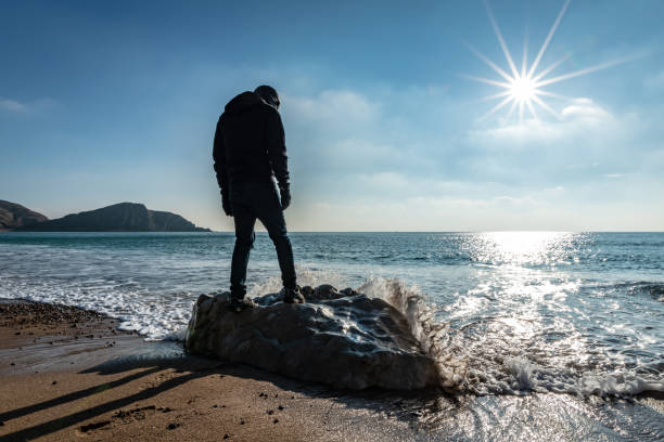 istock Man stands on large rock on Warbarrow Beach in Dorset, UK 1097423370