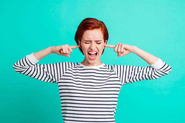 istock Portrait of nice pretty charming attractive sad red-haired lady wearing striped pullover closing ears with forefingers opened mouth isolated over bright vivid shine green turquoise background 1097427880