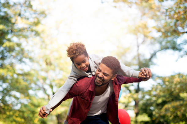 True moment of happiness. Happy child flying and piggyback. Father holding his daughter on shoulders and laughing. Happy child flying and piggyback. Father holding his daughter on shoulders and laughing. african father stock pictures, royalty-free photos & images