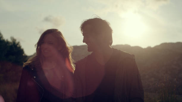 istock Couple walking along the rocky beach. Sunset 1097432402