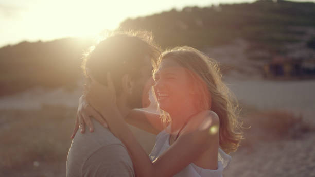 istock Couple cuddled together standing on the beach. Sunset 1097432756