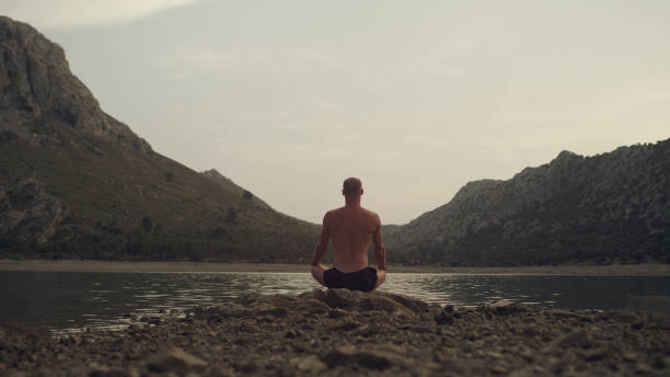 istock Man meditation. Rocky lake coastline 1097435546