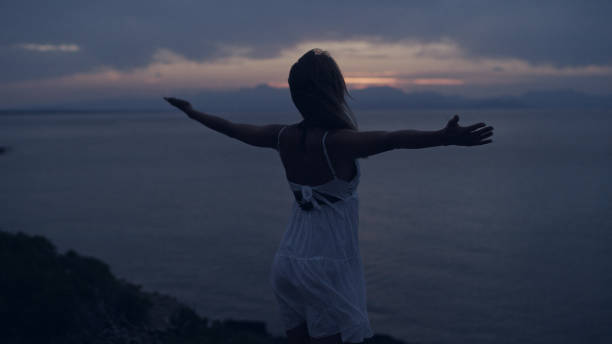 istock Woman meditating on rocky coastline. Open arms 1097435698