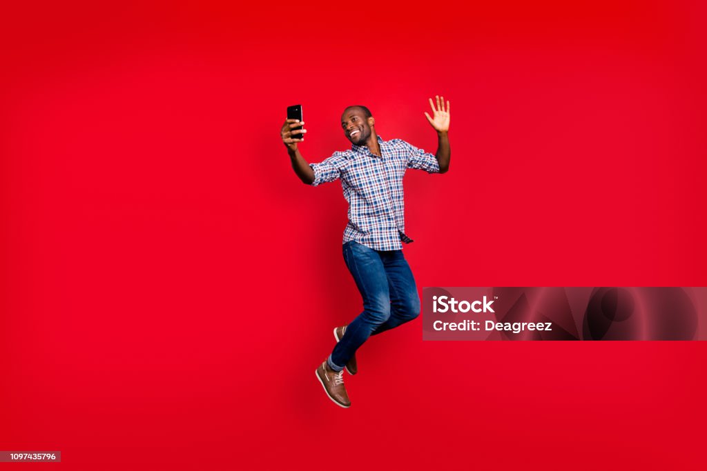 Full Length Body Size Of Nice Funny Crazy Handsome Cheerful Optimistic Guy  Wearing Checkered Shirt Holding In Hands Cell Waving Hi Hello Isolated On  Bright Vivid Shine Red Background Stock Photo -