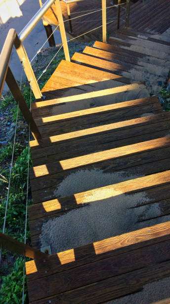 strome drewniane schody prowadzące w dół, piasek rozrzucony po schodach, promienie słoneczne grają na drewnie - steep road footpath moving down zdjęcia i obrazy z banku zdjęć
