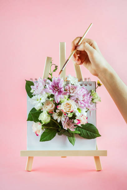 istock Woman's hands holding brush and drawing on easel with flowers 1097444330