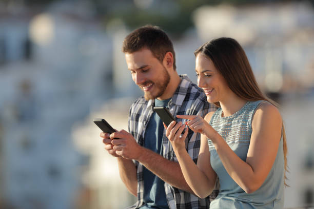 istock Couple using their smart phones in a town at sunset 1097446846