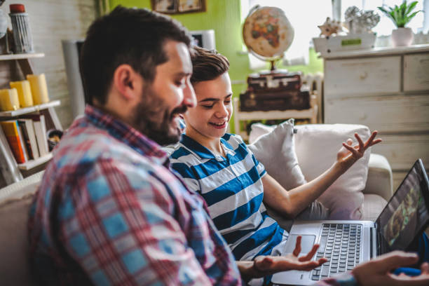 istock Smiling father and son using digital gadgets in living room 1097465518