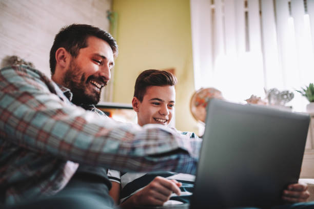 istock Smiling father and son using digital gadgets in living room 1097465620