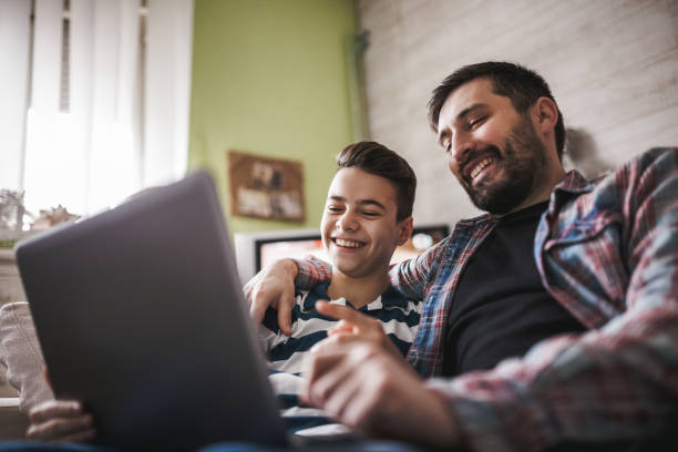 istock Smiling father and son using digital gadgets in living room 1097465934