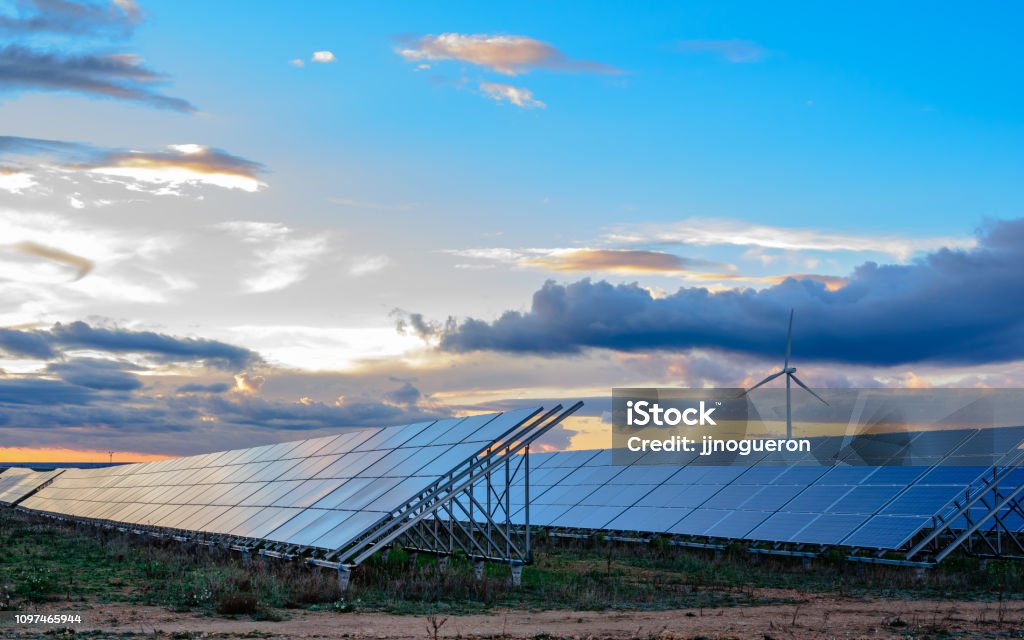 Solceller och vindkraft anläggning vid solnedgången - Royaltyfri Solenergi Bildbanksbilder