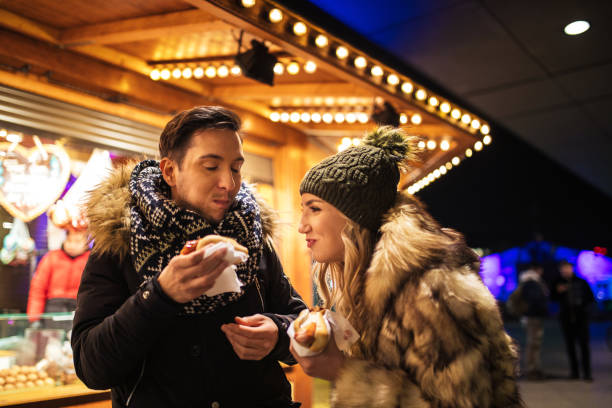 fröhliches paar genießt die leckeren würste auf einer straße stehen - 20s berlin germany heterosexual couple boyfriend stock-fotos und bilder