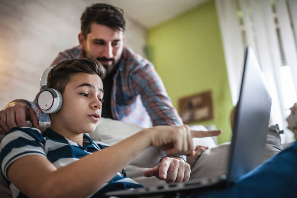 padre e figlio sorridenti che usano gadget digitali in salotto - computer child family laptop foto e immagini stock