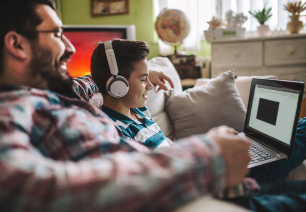 istock Smiling father and son using digital gadgets in living room 1097466360