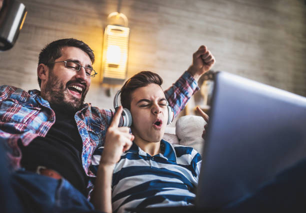 istock Smiling father and son using digital gadgets in living room 1097466500