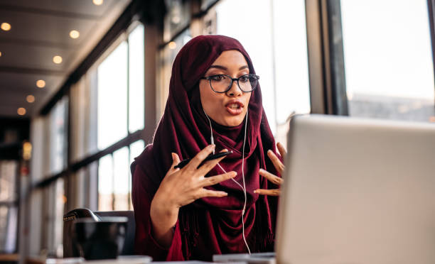 femme en hijab, avoir une conversation vidéo sur ordinateur portable - explaining photos et images de collection