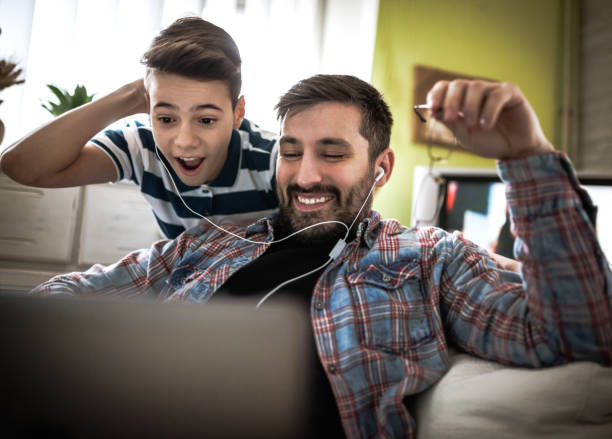 istock Smiling father and son using digital gadgets in living room 1097469680