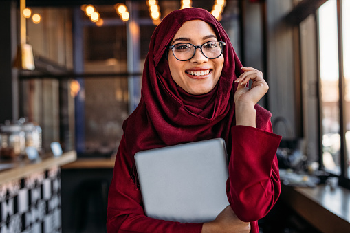 Sonriendo empresaria en hijab en cafetería photo